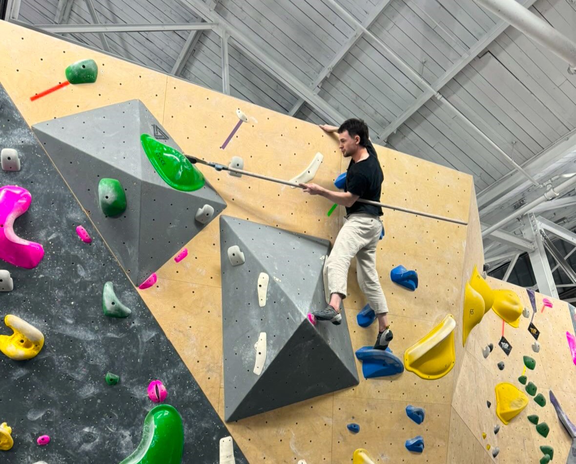 mak on the rock wall cleaning a hold with a brush